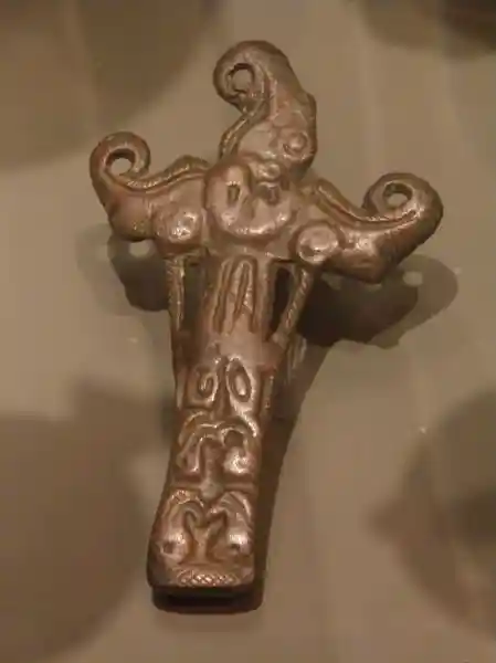 Bronze crucifix with upper three points curled, and symbols engraved on it